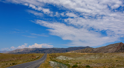 Wyoming prairie road, blue sky and mountains in the background. American road.