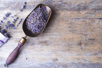 Lavender flowers in an antique scoop and lavender bouquet on wooden background. Top view.