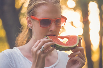 Beautiful woman eating watermelon outdoors