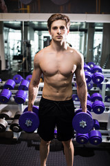 Naklejka premium very power athletic guy , execute exercise with dumbbells, in gym hall
