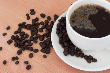 Hot coffee in white cup and coffee beans on the table