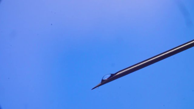 Water drop falling from the syringe needle