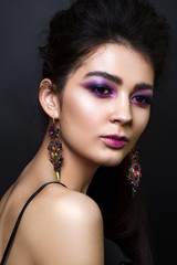 Portrait of beautiful young woman with professional makeup, perfect skin, big earrings Trendy lilac smoky eyes.