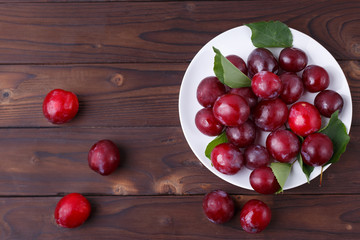 Delicious juicy fresh plums on plate on wooden table.