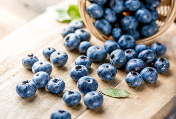 Freshly blueberries on wooden rustic wooden table. Juicy and fresh blueberries with green leaves. Bilberry on wooden background. Blueberry antioxidant. Concept for healthy eating and nutrition.