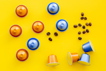 Beverage capsules for coffee mashine and grains on yellow background top view copyspace