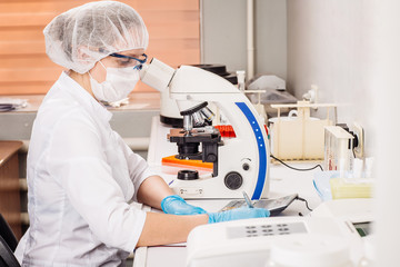 Professional scientist doing research with microscope in clinical laboratory. .