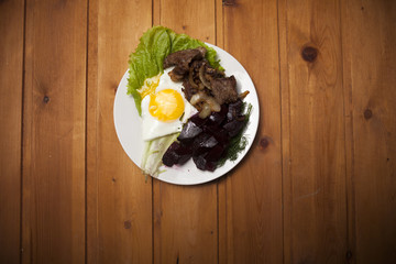 Breakfast of scrambled eggs, beets, pork and lettuce