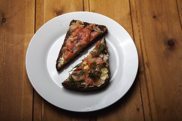 Two sandwiches with red fish on a white plate