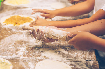 Making pastries from dough with stuffing. Children's hands close-up.