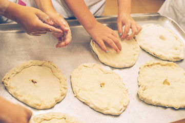 Making pastries from dough with stuffing. Children's hands close-up.