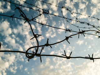 Barbed wire against the sky with clouds