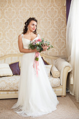 Beautiful young Bride with dark hairs in a bedroom. Classic white wedding dress. Half-length portrait
