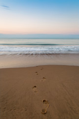 Vacation concept. Beautiful beach and sea during sunrise. Footstep in the sand.