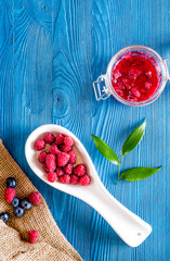 Homemade natural jam. Berries and sugar on blue wooden and canvas background top view