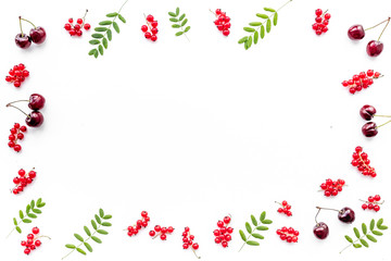 Berry frame. Red currant, cherry and leaves on white background top view copyspace