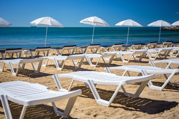 Beautiful empty beach with rows of sun beds under straw umbrellas