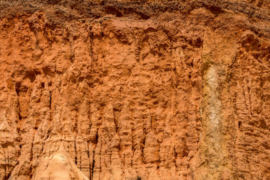 Close up view of red vertical sandstone cliff in Algarve Portugal.