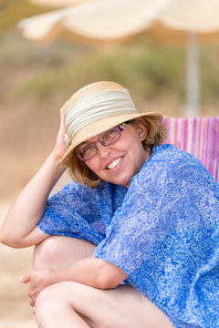 Beautiful summer portrait of middle aged woman in sun hat and glasses on the beach.