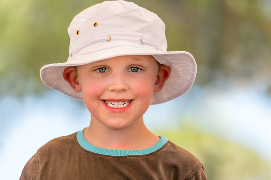 Outdoor summer portrait of cute smiling boy in white hat. Selective focus with shallow depth of field.