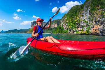 Woman paddles red kayak in a tropical sea