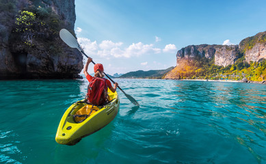 Woman paddles kayak in the tropical sea - obrazy, fototapety, plakaty