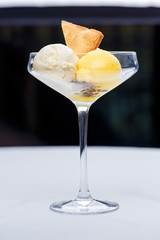 Two different scoops of ice cream with cake and passion fruit in a glass.