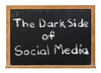 Obraz premium The dark side of social media written in white chalk on a black chalkboard isolated on white