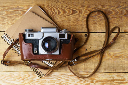 Old retro camera,  spiral blank kraft paper notebook on vintage rustic wooden planks boards. Education photography courses back to  school concept abstract background. Close up, horizontal, top view.