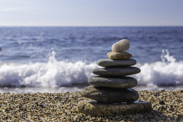 Fototapeta premium Balanced stones on the beach of Sardinia Island. Waves background.