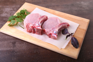 Raw pork steak with spices Leaves of coriander on wooden cutting board. Ready for cooking.