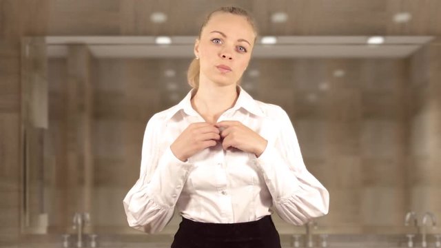 Joyful girl corrects her blouse in front of the mirror