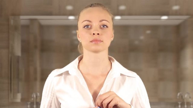 Joyful girl corrects her blouse in front of the mirror