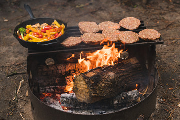 Cooking hamburgers and vegetables on camp fire