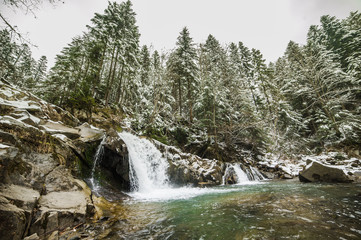Winter forest river with many waterfalls