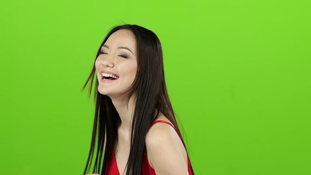 Asian girl posing in camera and she smiling. Green screen. Slow motion
