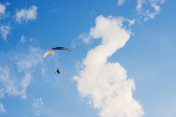 Paraglider flight in a cloudy blue sky