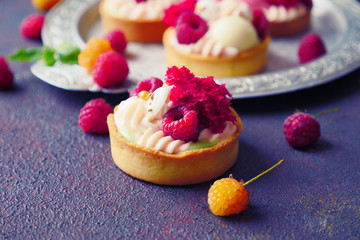 Cakes with strawberries and berries. Raspberry Cakes on dark background. Tasty Raspberry Tarts on a Vintage Plate. Wonderful Sweet Desserts. Mini tarts with Raspberries. Raspberry fruit tart.
