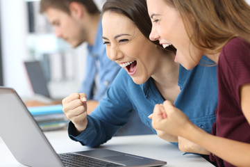 Excited businesswomen reading on line news