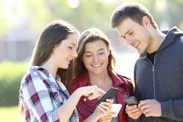 Three friends sharing on line content in the street