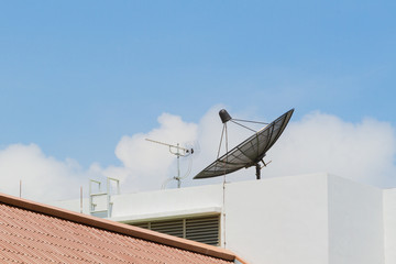 Antenna and satellite dish on the top of the building in the sky background, Thailand, Horizontal photo.