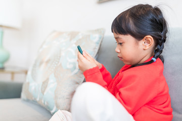 Asian girl looking at smart phone and sitting on sofa