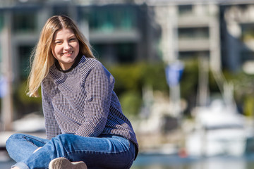 outdoor portrait of young happy smiling teen girl on marine background on a sunny day, auckland central wharf, new zealand