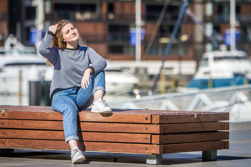 outdoor portrait of young happy smiling teen girl on marine background on a sunny day, auckland central wharf, new zealand