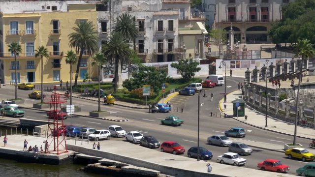 A high angle aerial tracking dolly establishing shot of traffic on the streets of Havana, Cuba, including colorful vintage American cars that are a popular tourist attraction. Shot in 5K.  	