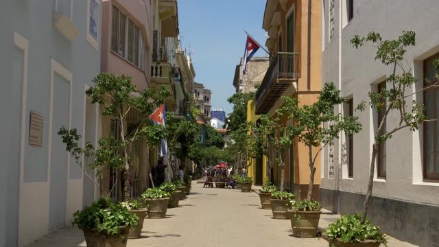 A daytime exterior establishing shot of a typical narrow street in the old town tourist district of Havana, Cuba. Shot in 5K.  	
