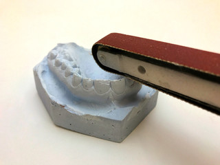 Dental gypsum model mould of teeth in plaster. Sanding machine making teeth smooth