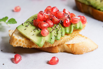 sliced avocado on toast bread with pomegranate seeds.