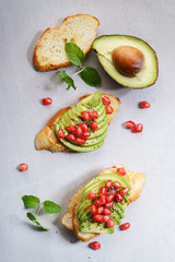 sliced avocado on toast bread with pomegranate seeds.