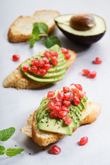 sliced avocado on toast bread with pomegranate seeds.